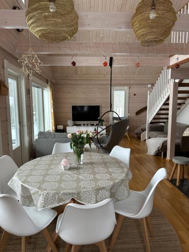a dining room with a table and white chairs at Villa Ihanus 100 m2 ja rantasauna järven rannalla in Kuusamo