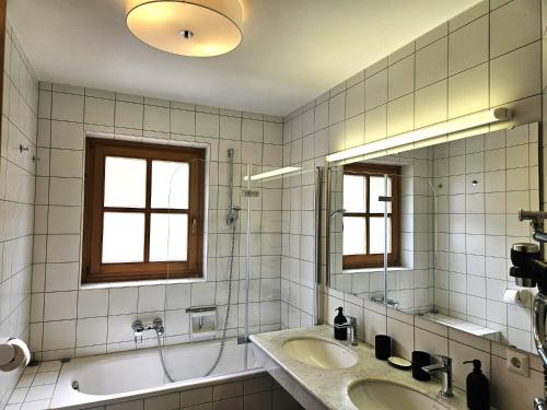 ein Badezimmer mit zwei Waschbecken und einer Badewanne und zwei Fenstern in der Unterkunft Deluxe Panorama Apartment-Maibrunn-Alm in Bad Kleinkirchheim