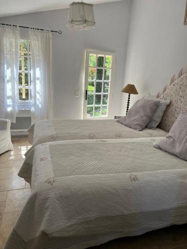 - une chambre avec 2 lits dotés de draps blancs et de fenêtres dans l'établissement Les Cyprès, à Lourmarin