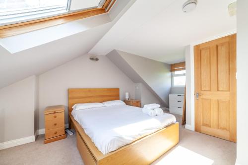 a bedroom with a bed with white sheets and a window at Charming Retreat West London - Spacious & Modern in Hanwell