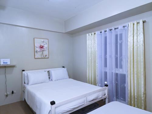 a white bedroom with two beds and a window at 1BR and Studio Condo Unit @ 150 Newport near NAIA 3 in Manila