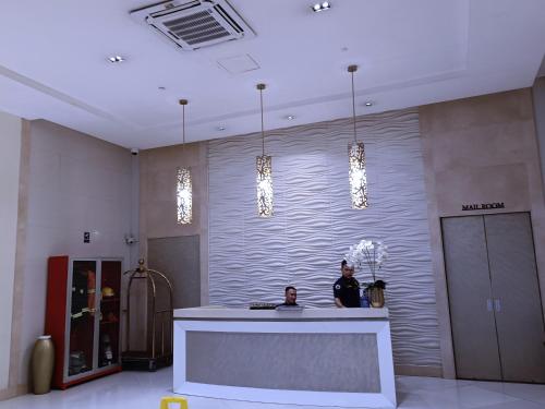 Due uomini in piedi davanti a un bancone in una hall di 1BR and Studio Condo Unit @ 150 Newport near NAIA 3 a Manila