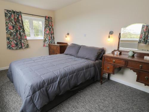 1 dormitorio con cama, tocador y espejo en Broadlands Bungalow en Chard