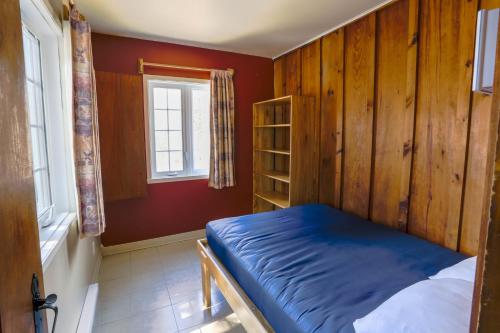 a bedroom with a blue bed and a window at Chalets Lanaudière in Rawdon
