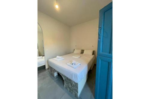 a small bedroom with a bed and a blue door at Politimis Studio N5 in Amorgos