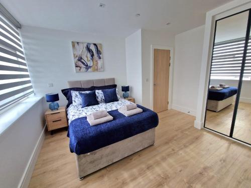 a bedroom with a blue bed and a mirror at Fabulous top floor 2 bedroom apartment in Chertsey in Chertsey