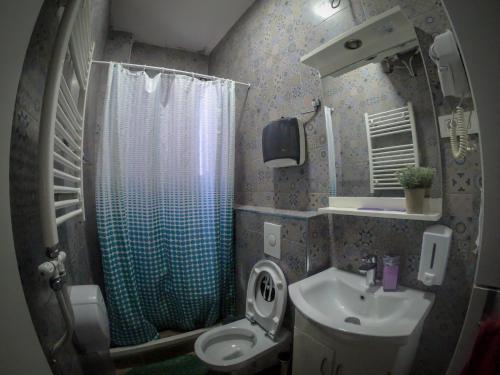 La salle de bains est pourvue de toilettes, d'un lavabo et d'une douche. dans l'établissement Hostel Charming Double Private Room, à Pristina