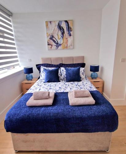 una camera da letto con un grande letto blu con due cuscini di Fabulous top floor 2 bedroom apartment in Chertsey a Chertsey