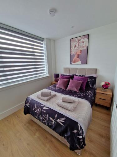 a bedroom with a bed with purple pillows and a window at Fabulous top floor 2 bedroom apartment in Chertsey in Chertsey