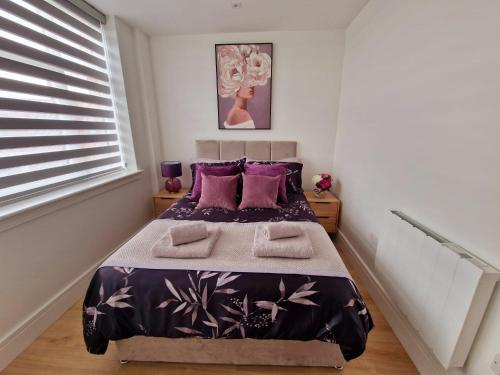 ein Schlafzimmer mit einem Bett mit lila Kissen in der Unterkunft Fabulous top floor 2 bedroom apartment in Chertsey in Chertsey