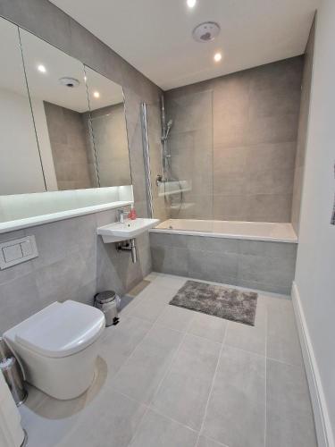 a bathroom with a toilet and a sink and a tub at Fabulous top floor 2 bedroom apartment in Chertsey in Chertsey