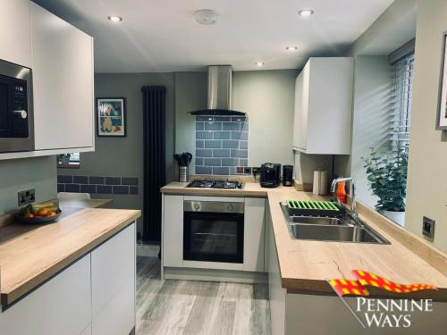a kitchen with white cabinets and a sink at Forge Cottage - Modern Cottage in Central Location in Haltwhistle