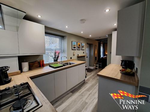 a kitchen with white cabinets and a sink at Forge Cottage - Centre of Britain in Haltwhistle