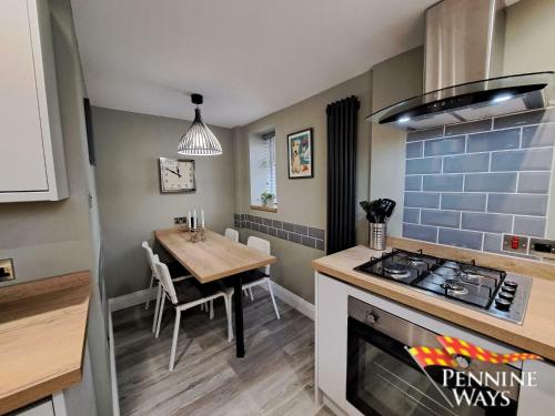 una cucina e una sala da pranzo con tavolo e piano cottura di Forge Cottage - Centre of Britain a Haltwhistle