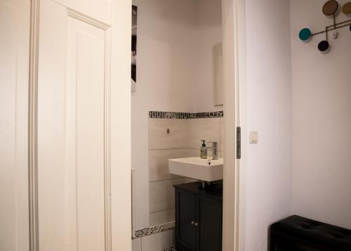 a white bathroom with a sink and a white door at Weinberg 100 in Dresden