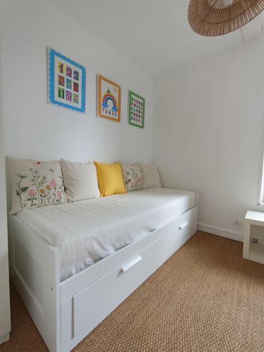 Una cama blanca en una habitación con algunas fotos en la pared en Le Refuge du Fou en La Forêt-sur-Sèvre