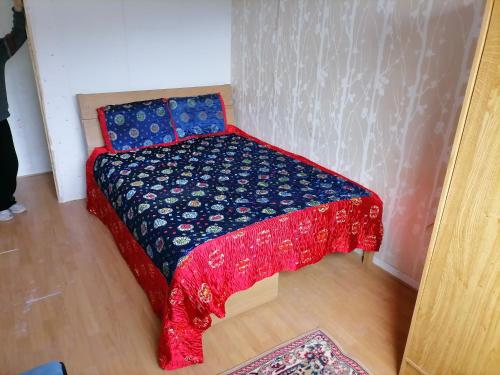 Cama pequeña en habitación con colcha roja y azul en Hôtel familial de Saint-Georges, en Villeneuve-Saint-Georges