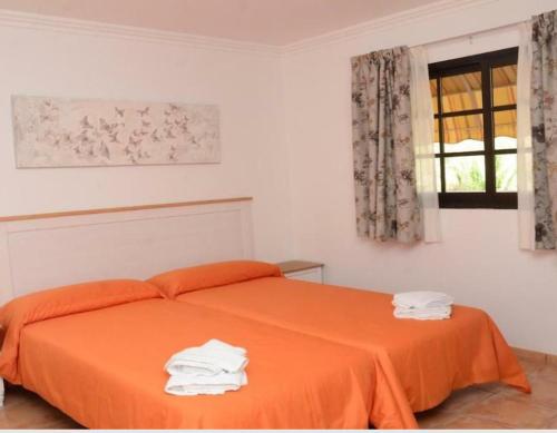 um quarto com uma cama com lençóis laranja e uma janela em Apartamentos Trasmallo 1 em La Playa Calera