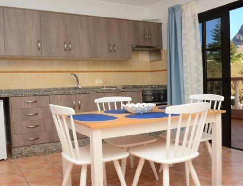 uma cozinha com uma mesa e cadeiras brancas numa cozinha em Apartamentos Trasmallo 1 em La Playa Calera