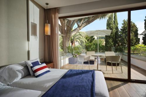 a bedroom with a bed and a view of a patio at Hotel Son Caliu Spa Oasis in Palmanova