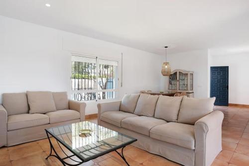 a living room with two couches and a glass table at Villa Escocia, entre pinares y a pie de playa in Roche