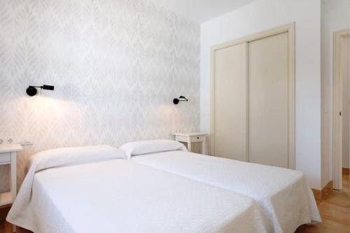 a white bedroom with a large bed with white sheets at Villa Escocia, entre pinares y a pie de playa in Roche