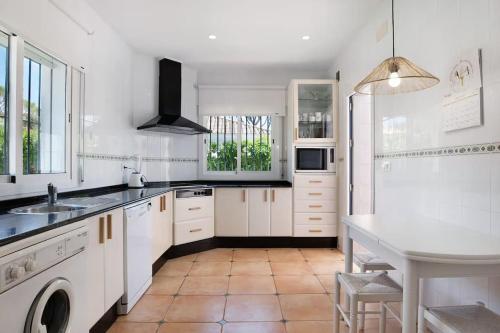 a white kitchen with a sink and a table at Villa Escocia, entre pinares y a pie de playa in Roche