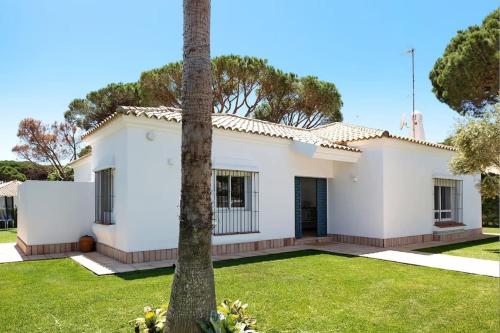 a white house with a palm tree in the yard at Villa Escocia, entre pinares y a pie de playa in Roche