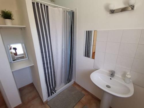 une salle de bain blanche avec une douche et un lavabo dans l'établissement Le Viel Olivier 4, à Cornillon