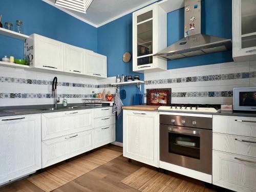 a kitchen with white cabinets and blue walls at Appartamento piano terra centro in Viareggio