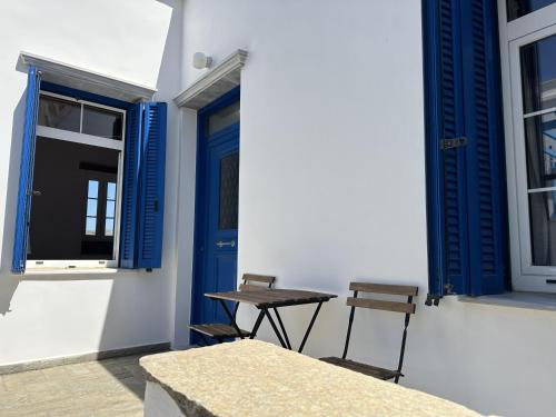 a table and chairs next to a building with blue windows at Anna's village house in Smardhákion