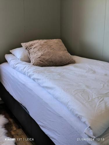a bed with white sheets and a pillow on it at Happy-Cove Guesthouse - by the sea in Bakkafjörður