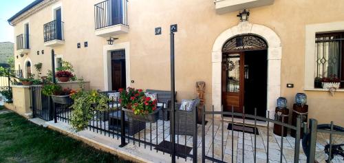 a building with a fence and flowers in front of it at La Dimora dei Baldi - Rooms & Relax in Fagnano Alto
