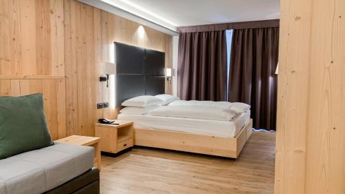 a hotel room with a bed and a couch at Hotel La Montanara Predazzo in Predazzo