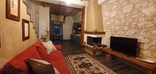 a living room with a red couch and a television at La Dimora dei Baldi - Rooms & Relax in Fagnano Alto