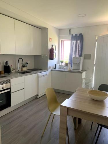 a kitchen with white cabinets and a table and a table and a dining room at Casa de Praia Quiaios in Quiaios