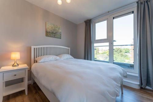 1 dormitorio con cama blanca y ventana en Luxury 2 Bed Apartment Parking by NEC & Solihull, en Solihull