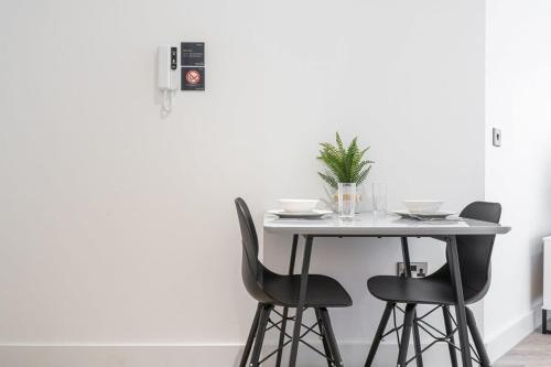 einen Tisch mit zwei schwarzen Stühlen und einem weißen Tisch in der Unterkunft Modern Studio Apartment - Solihull by Seven Stays in Solihull