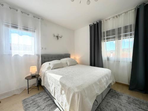 a white bedroom with a bed and a window at Terra Verde in Račički Brijeg