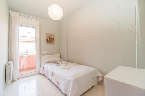 a white bedroom with a bed and a window at Casa para vacaciones perfectas in Vilassar de Mar