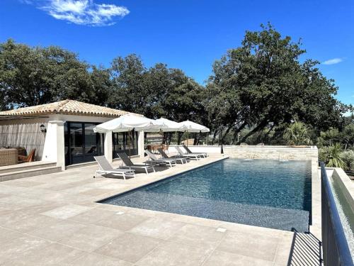 une piscine avec chaises longues et parasols dans l'établissement Villa Marie - Domaine Cavalery, à Pertuis