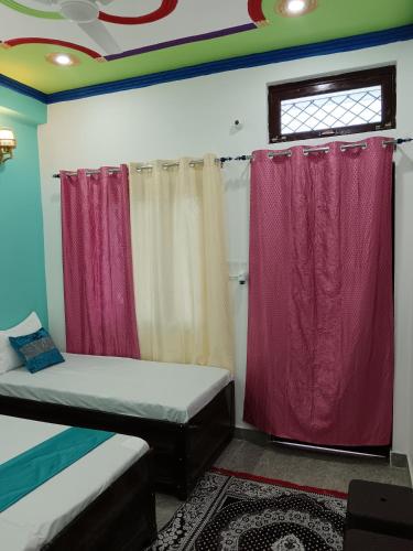 a room with two beds and red curtains at Hotel Tejas in Gupta Kāshi