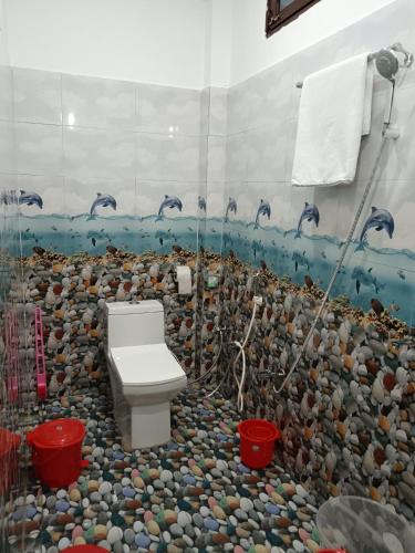 a bathroom with a toilet and dolphins on the wall at Hotel Tejas in Gupta Kāshi