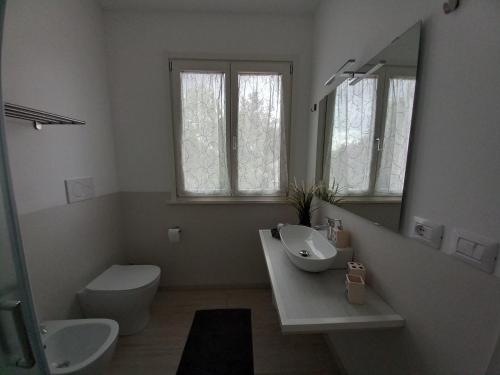 een badkamer met een wastafel, een toilet en een spiegel bij B&B IL NIDO in Cattolica