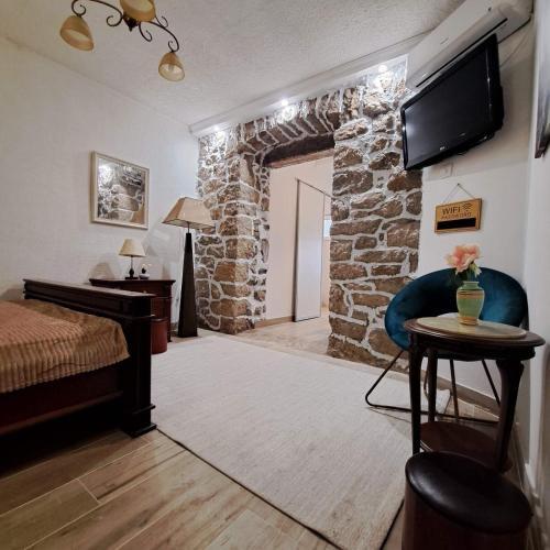 una camera da letto con un muro in pietra, un letto e una TV di Unique Apartment Centar a Podgorica
