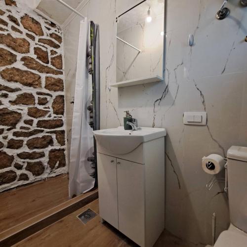 bagno con lavandino e parete in pietra di Unique Apartment Centar a Podgorica