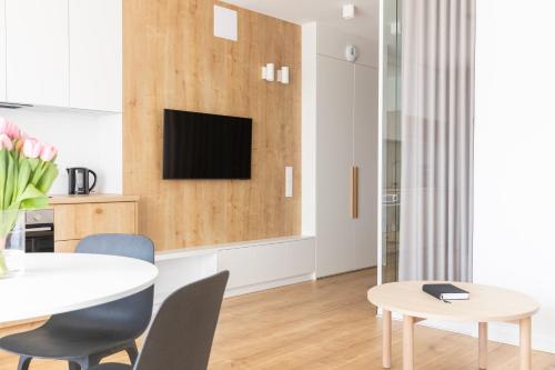 a living room with a table and a tv on a wall at Kamienica Parkowa in Dąbki