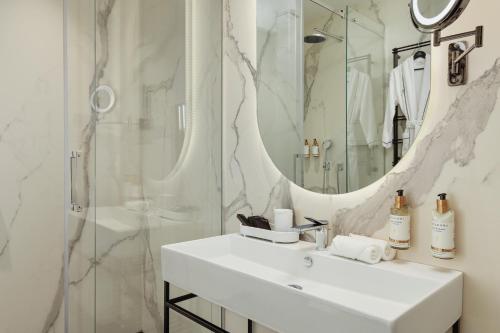 a white bathroom with a sink and a shower at Porto Palace Residences in Tivat