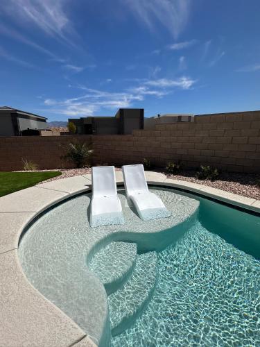 two white chairs sitting in a swimming pool at 4BR Oasis - Pool and Spa - Near Golf and Casinos in Mesquite