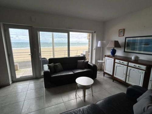 uma sala de estar com um sofá e vista para a praia em Appartement sur la plage em Pléneuf-Val-André